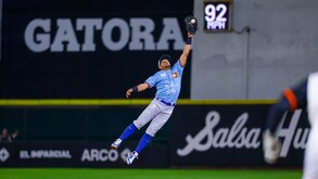 Un jugador de los Charros de Jalisco salta espectacularmente con el guante extendido para atrapar una pelota durante un juego nocturno.
