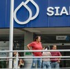 Fachada de una oficina del SIAPA con su logotipo azul y blanco; varias personas esperan afuera detrás de un barandal metálico cerca de la entrada.