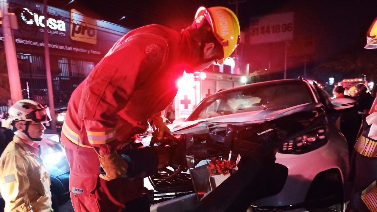 Bomberos de Guadalajara realizando maniobras con herramientas sobre una camioneta blanca con el cofre levantado