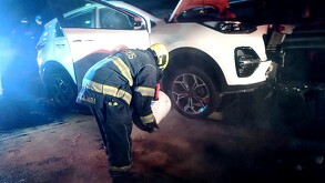 Bombero de Guadalajara sosteniendo una cubeta inclinado sobre la llanta de una camioneta blanca después de un choque