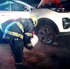 Bombero de Guadalajara sosteniendo una cubeta inclinado sobre la llanta de una camioneta blanca después de un choque
