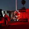 Una grúa de rescate trabaja durante la noche para levantar un camión de carga pesado que ha volcado sobre su costado en una carretera iluminada.