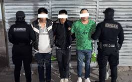 Tres sujetos detenidos y policías en los lados