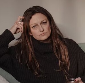 Claire sentada en un sillón viendo fijamente a la cámara