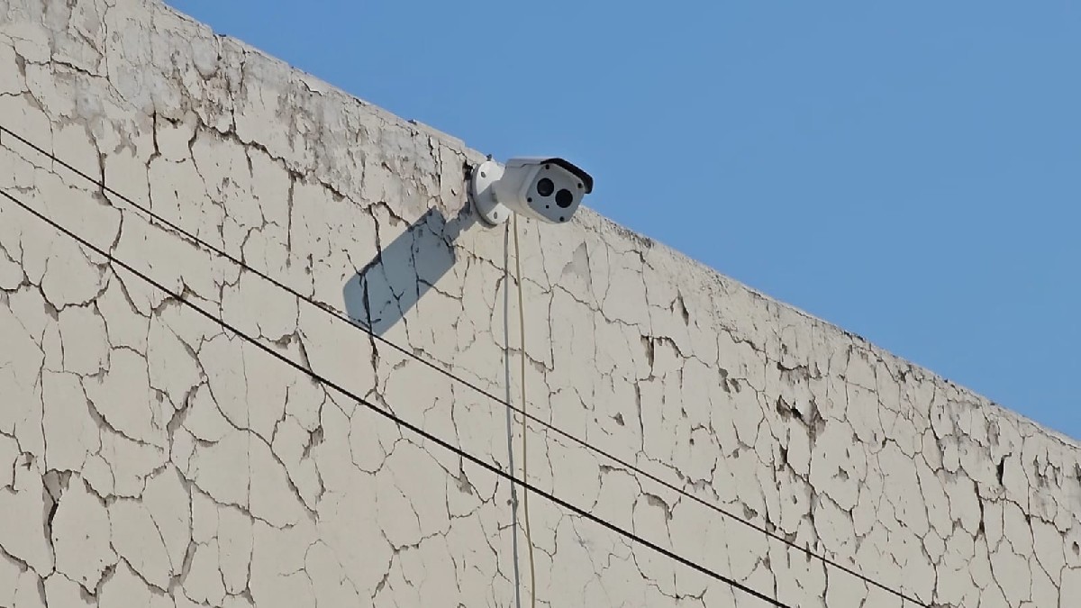 Una patrulla de la Policía Municipal de Zapopan está estacionada en el patio de una zona residencial moderna, vista a través de una reja metálica.