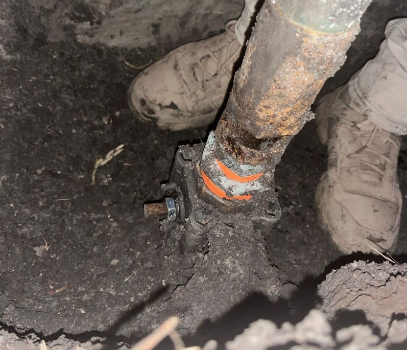 Tubería enterrada en una finca para el robo de combustible y unas botas cafés vistas detrás del tubo
