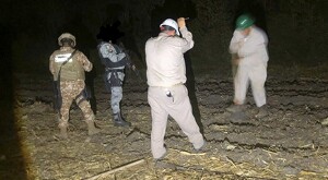 Oficiales de la Secretaría de Defensa sosteniendo armas largas y palas en medio de un descampado durante la noche