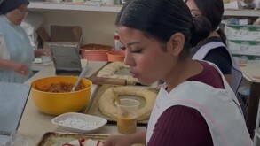 Se observa a una mujer haciendo una rosca de reyes sobre una mesa.
