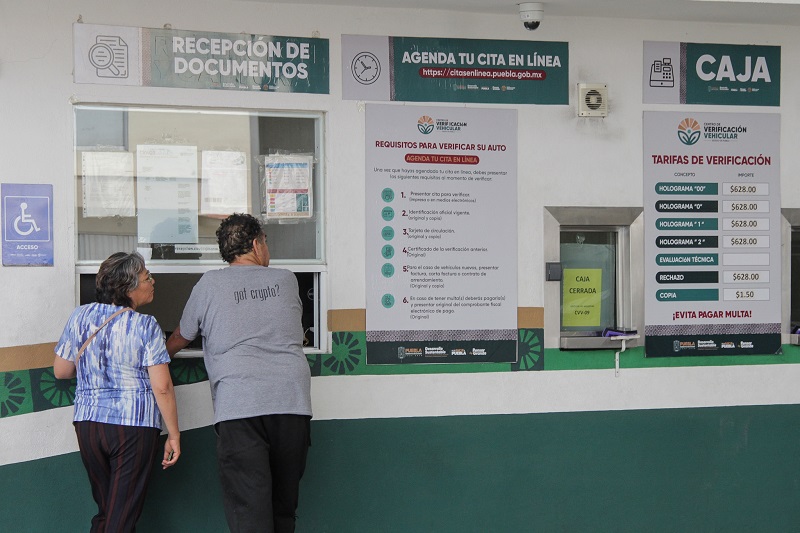 Dos personas formadas en la ventanilla de un verificentro en Puebla.