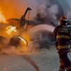 Bomberos de Tlaquepaque lanzando agua con una manguera a uno de los camiones consumidos por las llamas en el incendio dentro de una cementera