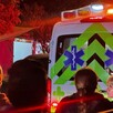 Vista de la parte trasera de una ambulancia de la Cruz Verde con la sirena encendida y personas observando alrededor