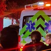 Vista de la parte trasera de una ambulancia de la Cruz Verde con la sirena encendida y personas observando alrededor