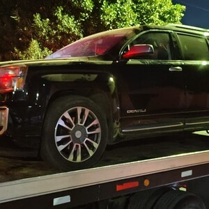 Camioneta en color negro arriba de grúa tras accidente