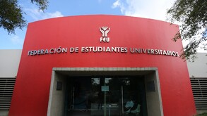 Fachada de un edificio con un gran muro rojo donde se lee 