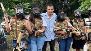 Un hombre posa para una foto junto a otras personas con armas falsas, vestidas con un uniforme táctico.