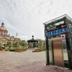 El elevador de cristal de la estación Guadalajara Centro destaca en primer plano, con la Catedral Basílica de fondo bajo un cielo parcialmente nublado.
