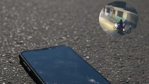 Celular en color negro tirado en carpeta asfáltica