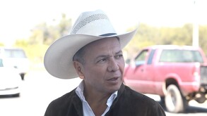 El gobernador Pablo Lemus viste una camisa blanca, chaqueta oscura y un sombrero de charro color crema, durante un evento al aire libre bajo el sol.