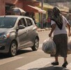 Se observa a una adulta mayor con bolsas en la mano en medio de una calle.