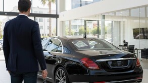 Persona de espaldas viendo su nuevo carro mientras sostiene las llaves del mismo en la mano.