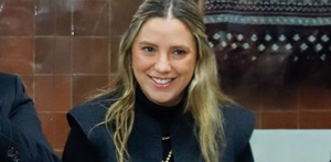 Mujer de cabello rubio sonríe ante la cámara en una entrevista.