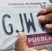 Persona sostiene con la mano sus placas de Puebla recién emitidas.