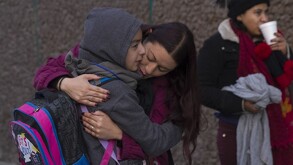 Se observa a un niño con sudadera y gorro puesto, abrazando a una mujer.