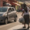 Se observa a una adulta mayor con bolsas en la mano en medio de una calle.