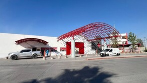Se observa un edificio color blanco con roja y una cruz roja.