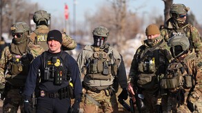 Agentes federales permanecen frente al edificio federal Bishop Henry Whipple al tiempo que los manifestantes se reúnen, en Minneapolis, el viernes 9 de enero.