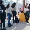 Se observa a varias personas haciendo una fila afuera de un edificio.