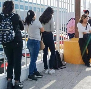 Se observa a varias personas haciendo una fila afuera de un edificio.