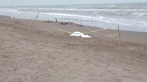 un cuerpo sin vida de un adolescente cubierto con una manta blanca en una playa de veracruz
