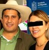 Un hombre con sombrero de palma y camisa verde posa sonriente junto a una mujer con gafas oscuras, frente a un banner de la Secretaría del Migrante.