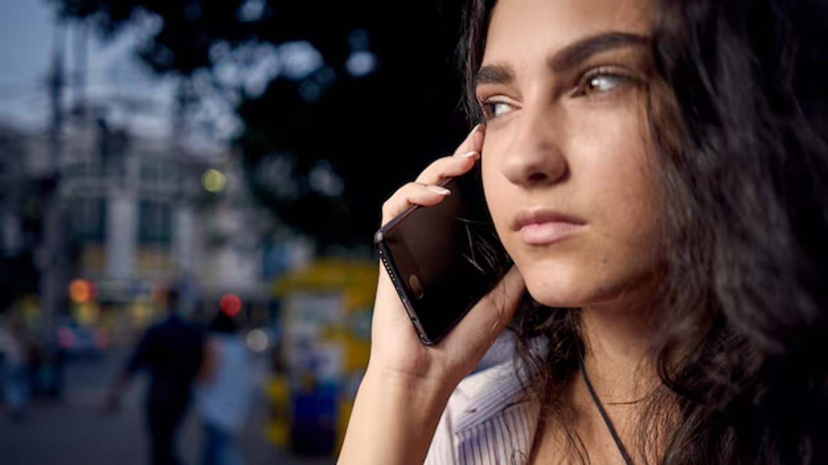 Mujer viendo hacia un lado mientras sostiene un teléfono celular roto de la pantalla con un fondo desenfocado