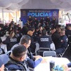 Decenas de oficiales sentados en mesas asisten a un evento bajo una carpa blanca, donde un banner al fondo dice: 