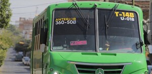 Vista frontal de un camión color verde de la ruta 50B circulando por calles de Guadalajara con casas y autos alrededor