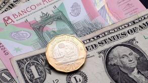 Dólares estadounidenses con billetes y moneda de 20 pesos mexicanos.