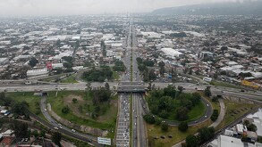 Vista aérea de un trébol vial sobre la Avenida López Mateos en Guadalajara, con intenso flujo vehicular y zonas industriales a los costados.