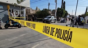 Patrullas de la Policía de Zapopan con oficiales municipales y militares de la Guardia Nacional detrás de una cinta policiaca con una moto y personas alrededor
