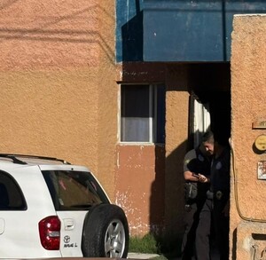 Se observa una camioneta blanca, atrás a unos hombres afuera de un domicilio.