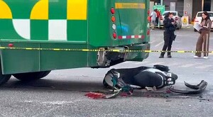 Parte trasera de un camión verde de la ruta 645 en Guadalajara con una motocicleta tumbada debajo con trozos esparcidos alrededor y una cinta policiaca