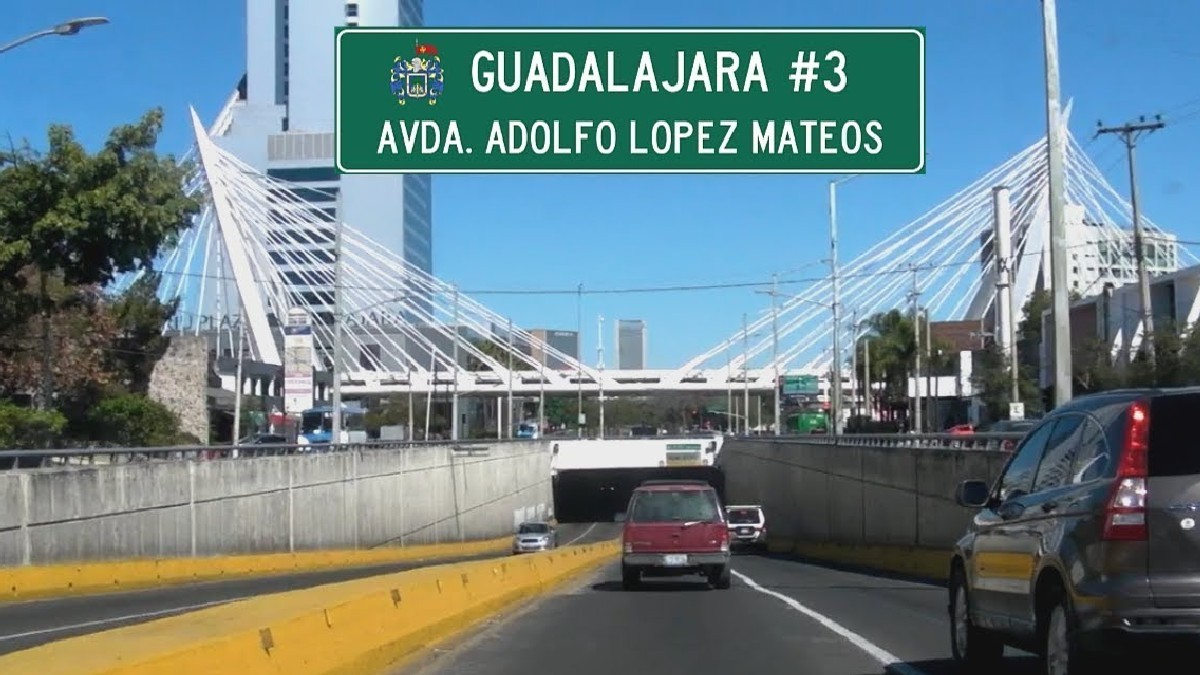 Vista aérea de un trébol vial sobre la Avenida López Mateos en Guadalajara, con intenso flujo vehicular y zonas industriales a los costados.