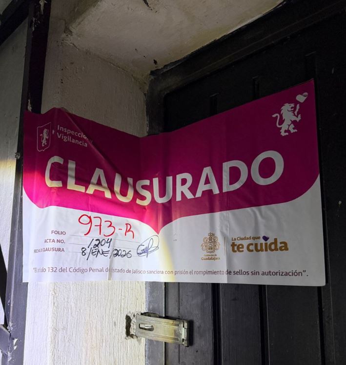 Sello de clausura del Gobierno de Guadalajara colocado en una puerta metálica color negro y parte de un muro de concreto blanco