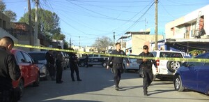 Se observan a varios hombres vestidos de negro caminando sobre la calle y hay una cinta amarilla de precaución.