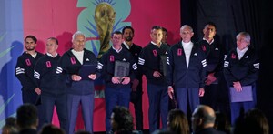 Un grupo de hombres con chamarras deportivas negras posa frente a un logo de la Copa Mundial de la FIFA 2026 durante un evento de presentación.