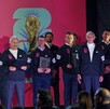 Un grupo de hombres con chamarras deportivas negras posa frente a un logo de la Copa Mundial de la FIFA 2026 durante un evento de presentación.