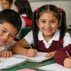 Niños de primaria en un salón de clases sonriendo a la cámara. Beca Rita Cetina.