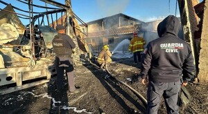 Bomberos de Michoacán junto con policía estatal y Guardia Civil arrojando agua a una vivienda para controlar un incendio