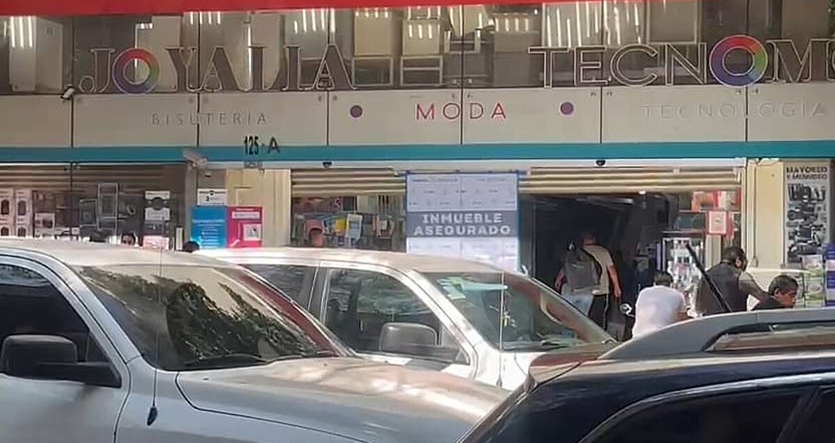 Cartel de Inmueble Asegurado colocado por la Fiscalía de Jalisco al exterior de una plaza en el centro de Guadalajara con autos y personas alrededor